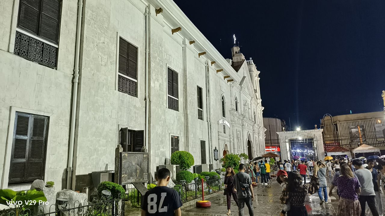 People walking in the rain outside a church, seeking shelter from the downpour