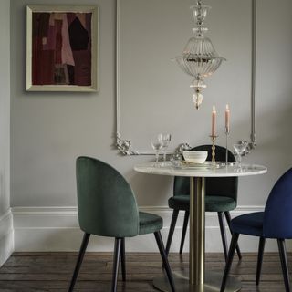 elegant dining room with glass pendant light and blue and green dining chairs