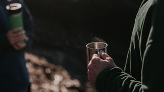 Man's hand holding a thermal mug