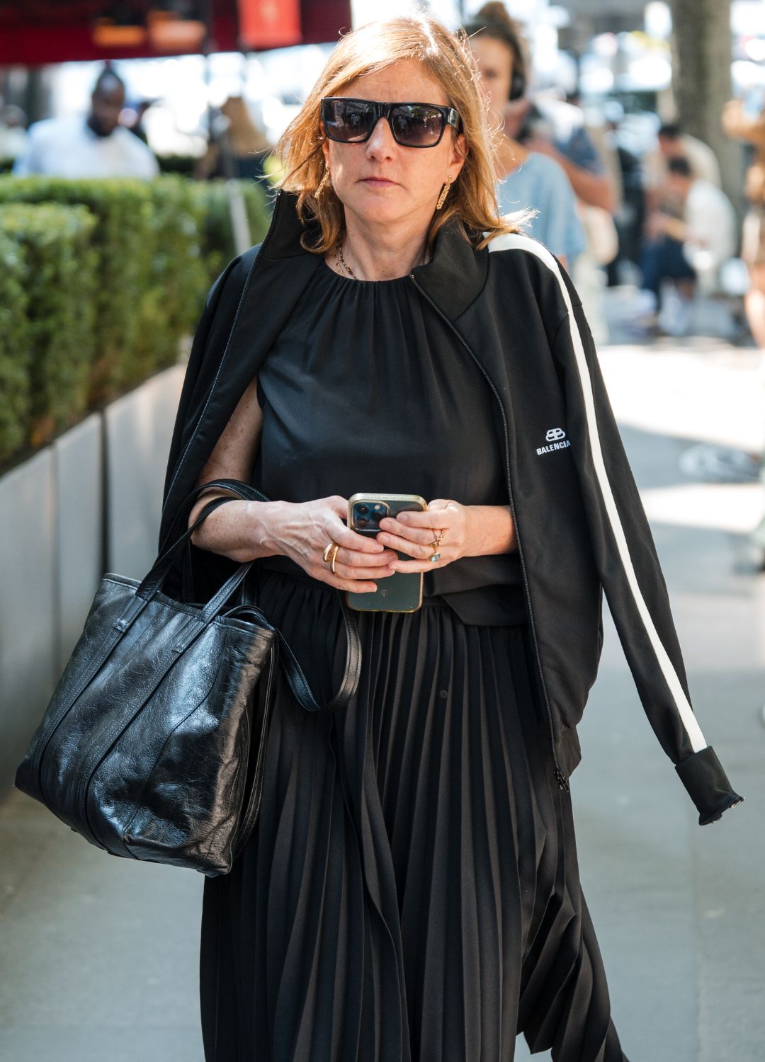 A guest wears black top, black Balenciaga sweatshirt, black pleated skirt, black bag, outside Balenciaga, during the Haute Couture Fall/Winter 2024/2025 as part of Paris Fashion Week on June 26, 2024 in Paris, France.