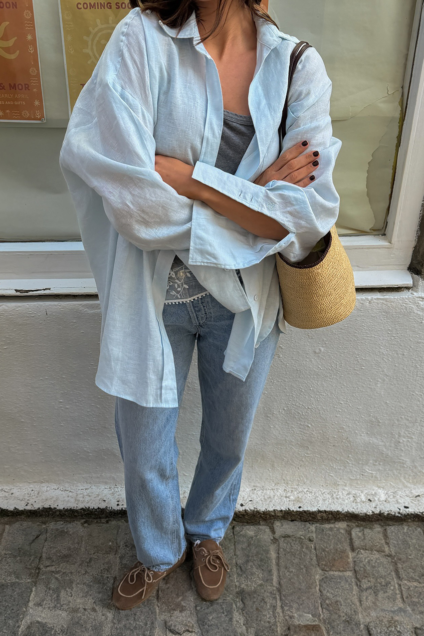 a woman wearing an oversized button-down, blue baggy jeans, and suede boat shoes