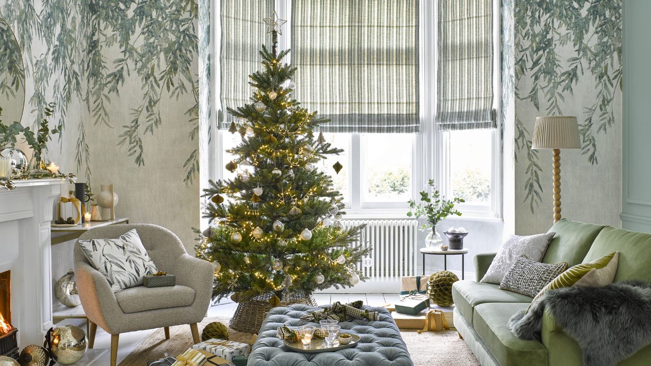 A living room with a botanical wallpaper decorated for Christmas with a fully decorated Christmas tree with lights, ornaments, a tree skirt and a topper