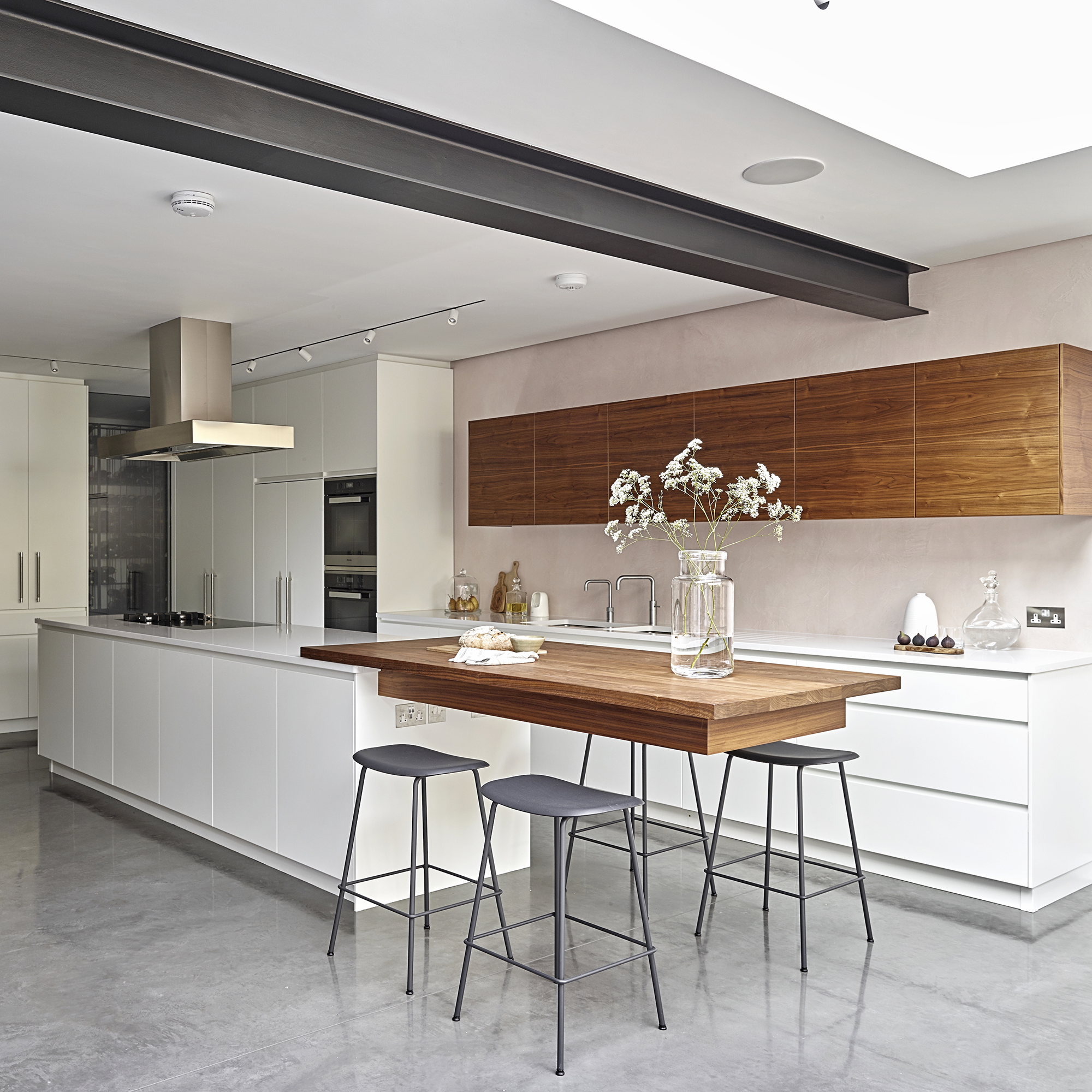 white kitchen with wooden bar table and stools