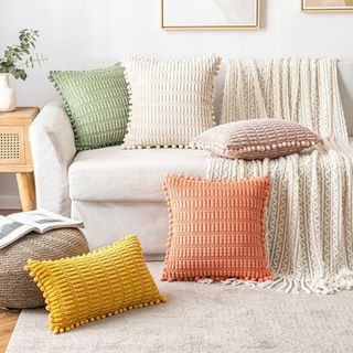 Colorful, textured throw pillows on a sofa and on the floor in front