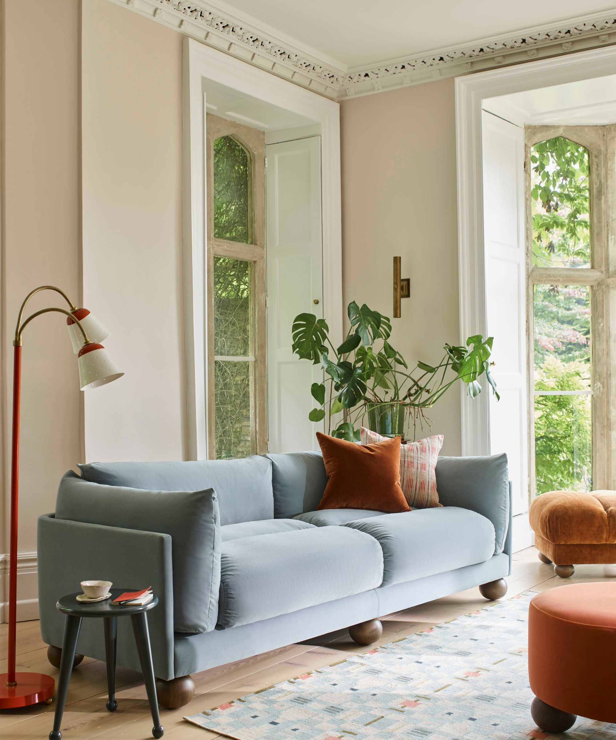 A large pale blue fabric sofa with wooden spherical ball feet.
