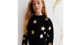 black jumper with gold stars illustrating the best christmas jumpers