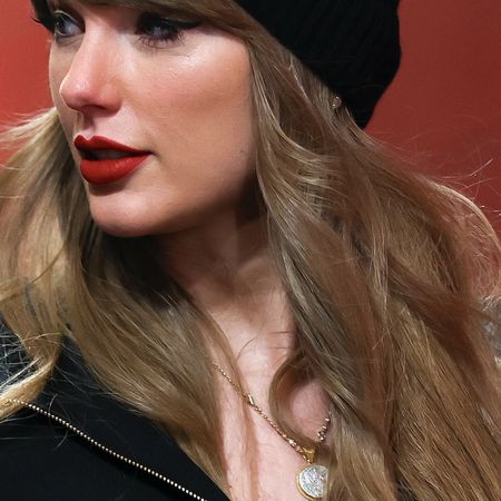 Taylor Swift wears a Louis Vuitton logo print jacket, black beanie, and a necklace possibly teasing Reputation Taylor's Version