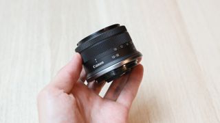 A Canon RF-S 10-18mm f/4.5-6.3 IS STM lens held in a hand