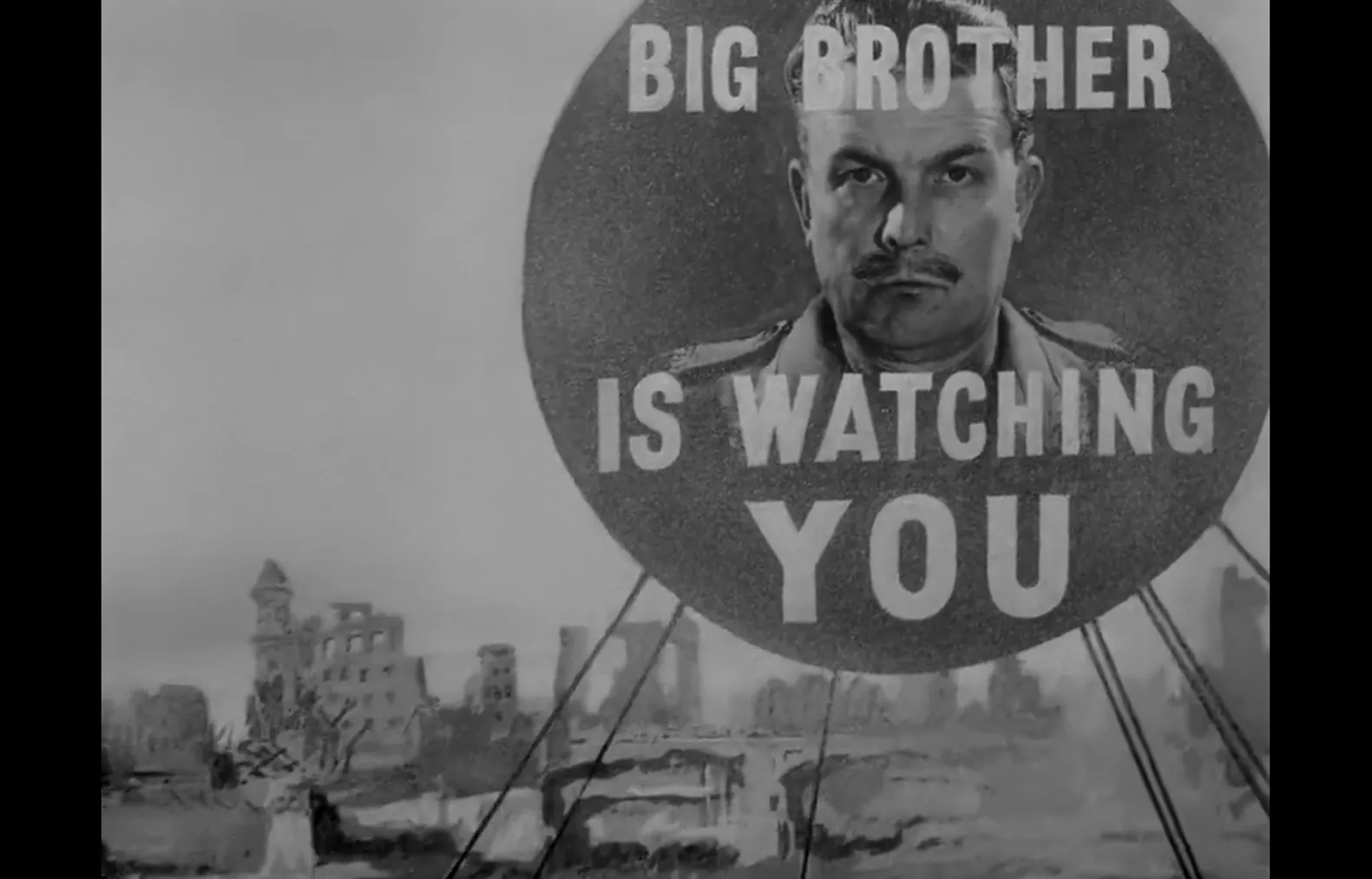 A circular billboard reading 'Big Brother Is Watching You' looms over a city of rubble, in a black-and-white still from Raoul Peck's 'Orwell: 2+2=5.'