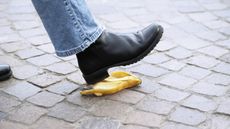 A person is about to step on a banana peel on the pavement.