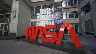 The red NASA sign is in front of a building.