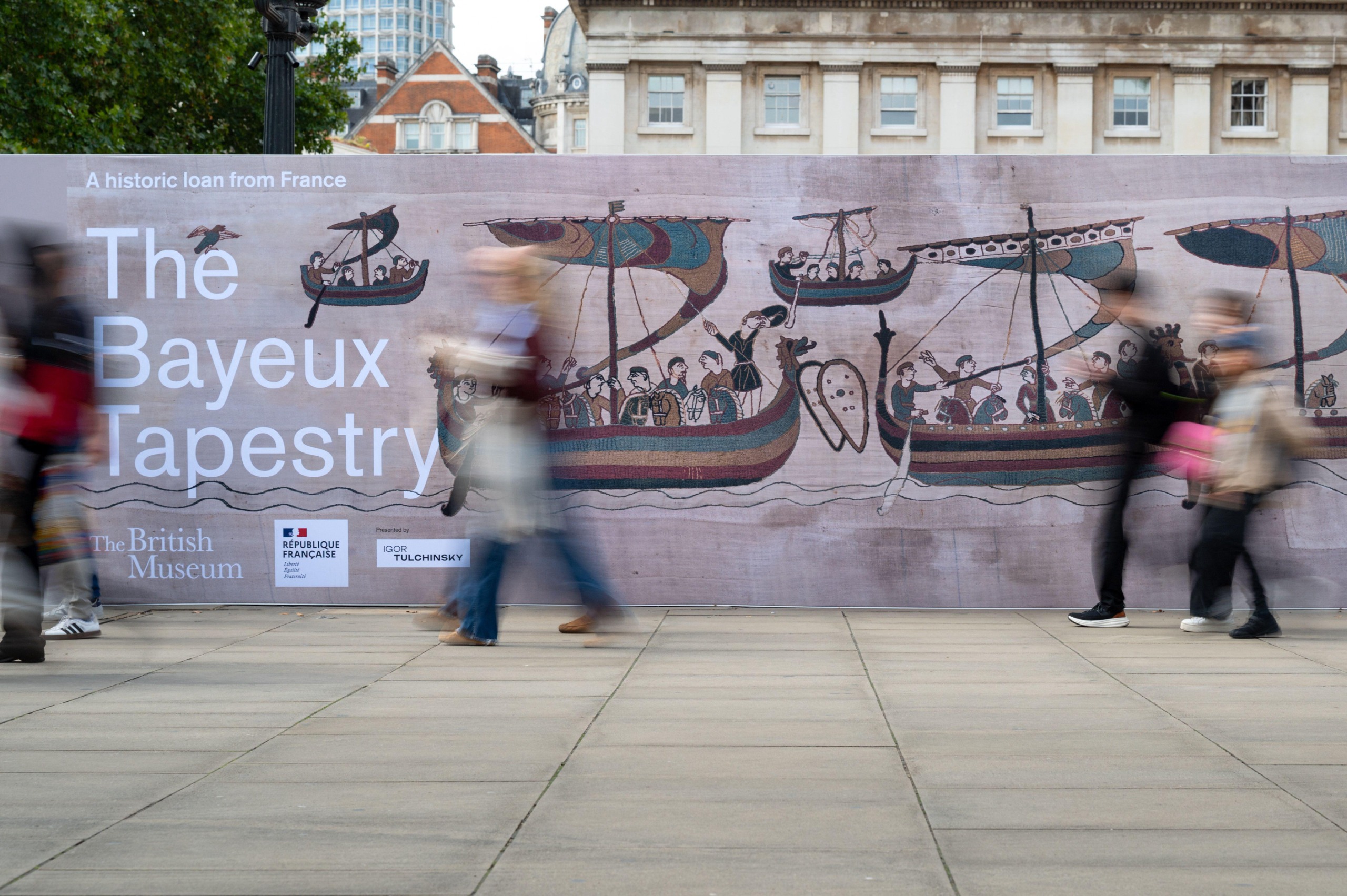 People walk past the advertising hoarding for the Bayeux Tapestry outside of the British Museum