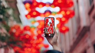 A tourist tries to take pro photos with iPhone at a city sight with red lanterns