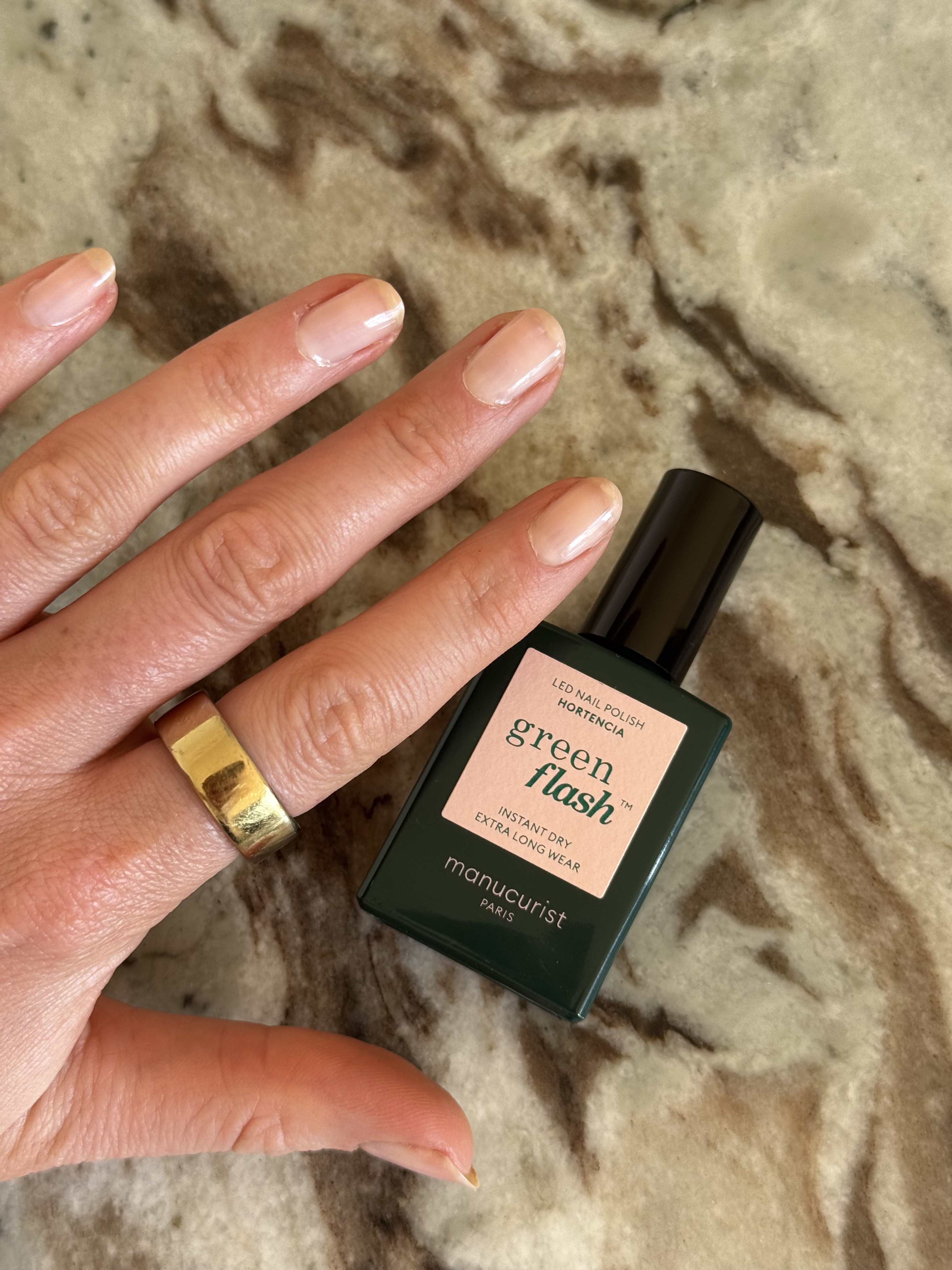 A photo of beauty editor Eleanor's hand, wearing a gold ring, with her nails painted in Manucurist Hortencia