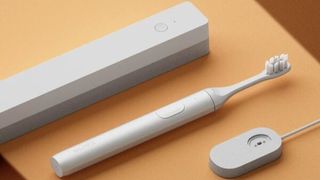 A white SURI electric toothbrush with its matching case and charger