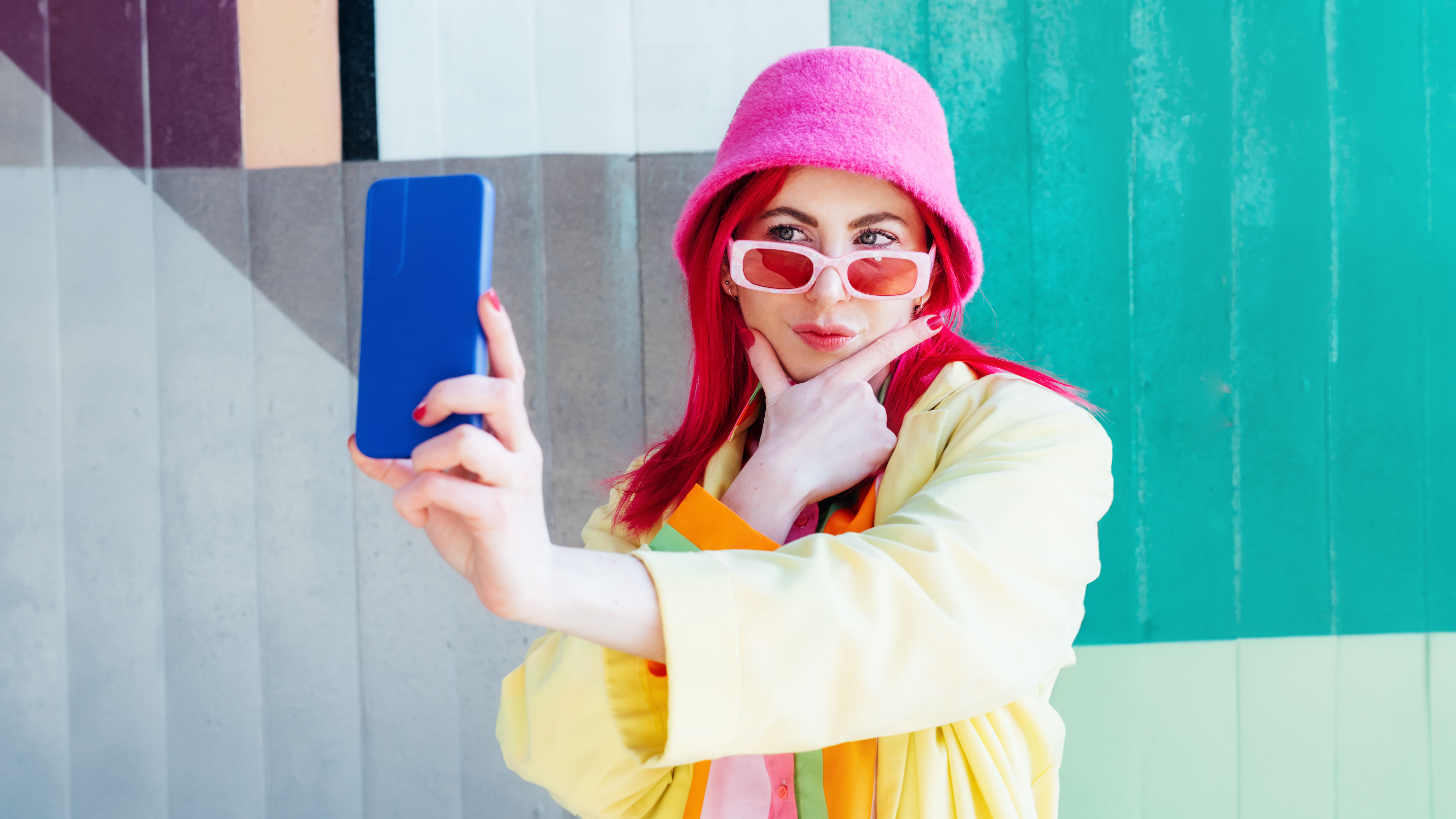 Pink hair woman taking selfie photo on graffiti background.