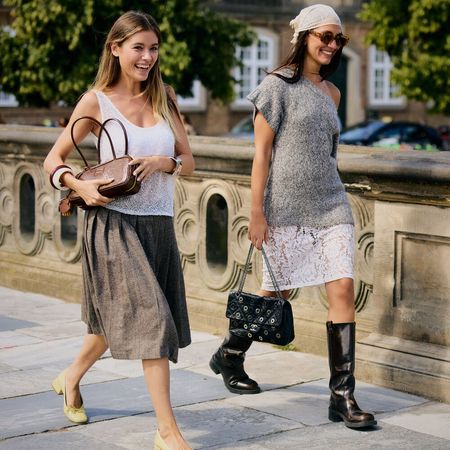 Two people wear cute outfits in Copenhagen. One wears a skirt and white tank while the other wears white skirt and gray knit top with white bandana. 