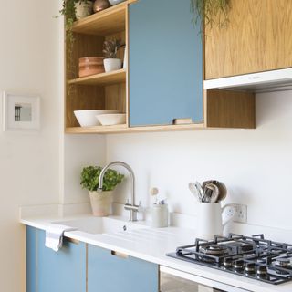 white kitchen worktop with gas hob and kitchen sink underneath blue cabinet