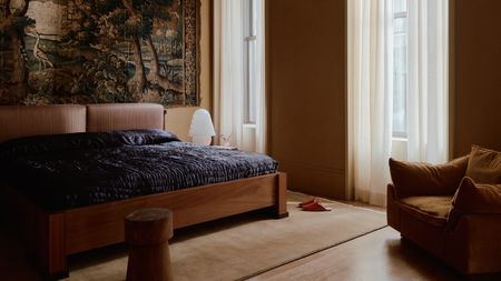 a pale yellow bedroom with dark blue bedding and a large wall tapestry