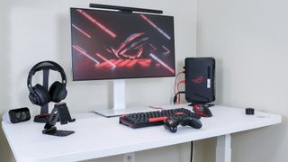 The Asus ROG NUC 970 on a desk with a monitor, keyboard, controller and headphones