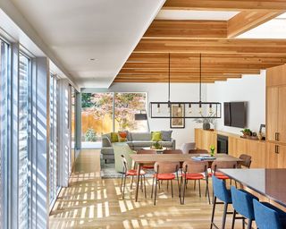 A bright modern open plan kitchen dining living room with exposed beams and lots of wooden finishes