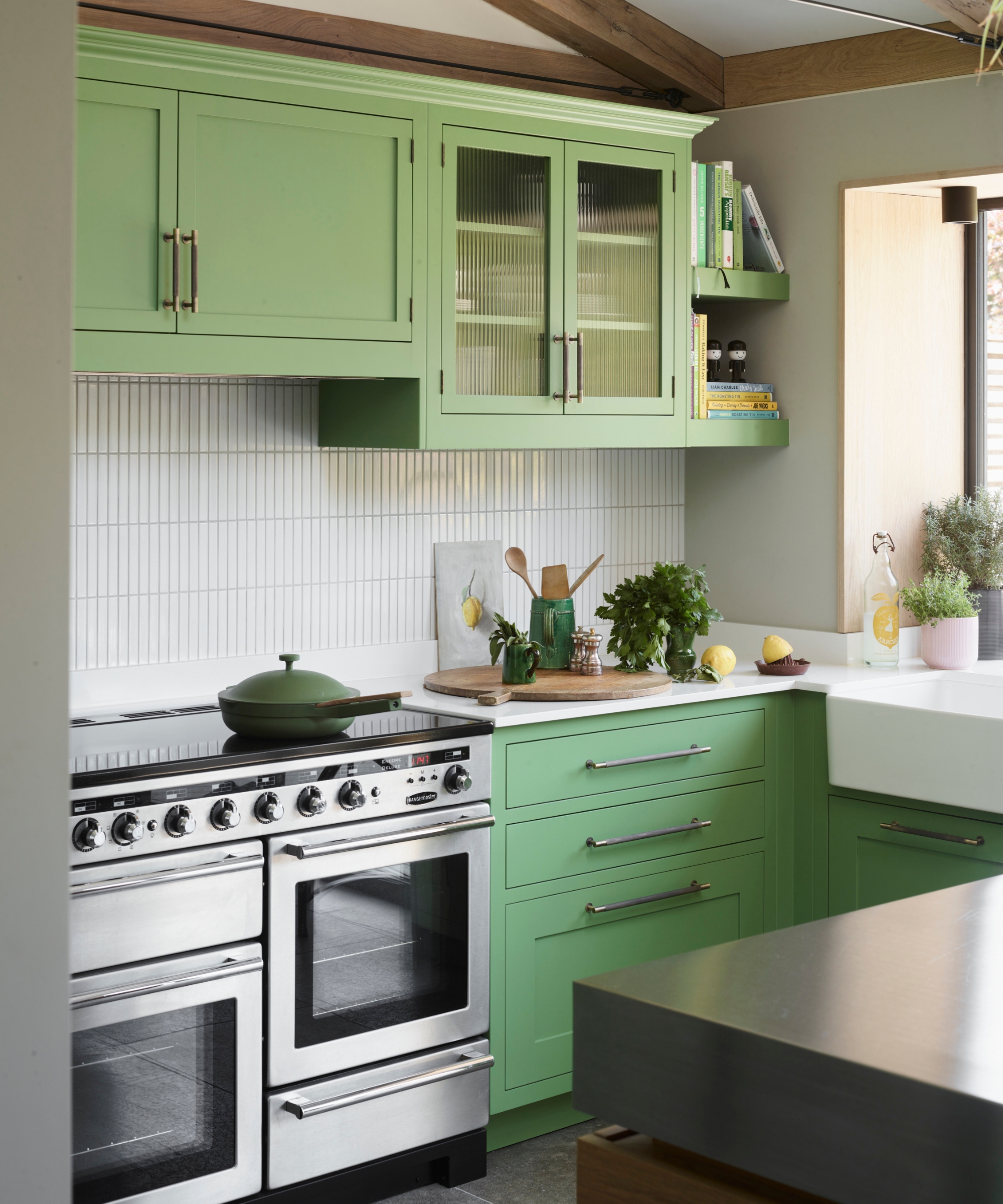 A green kitchen with white tiled subway splashback