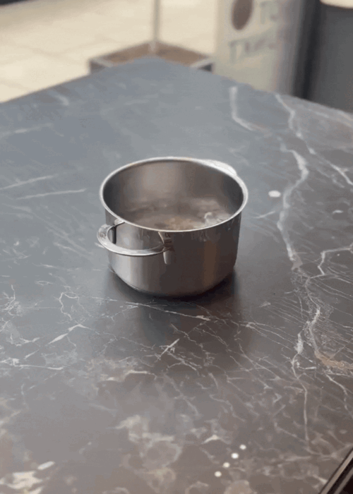 A pan of water boiling on an invisible hob