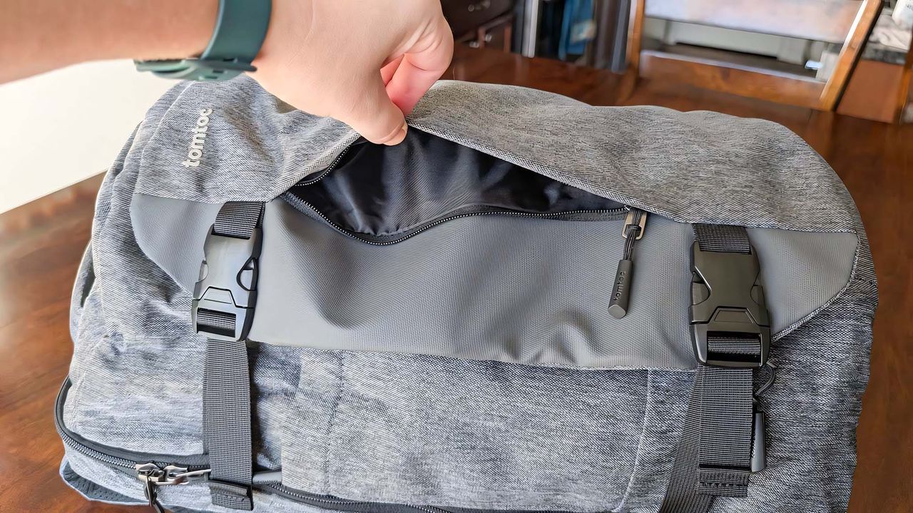 Tomtoc Navigator-T66 on its side with the top pouch being opened by a hand..