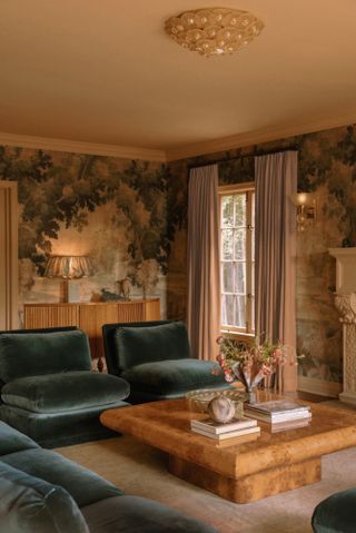 Living room with traditional mural on walls, blue-green velvet sofa, burr wood coffee table