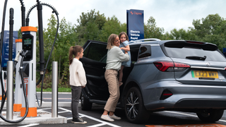 A woman lifts her child out of her electric car as they charge their vehicle at an Osprey Charging Network point