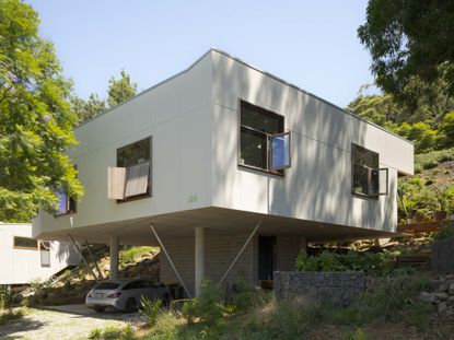 a white boxy house, scarborough house in australia, among wooded setting and with colourful furniture