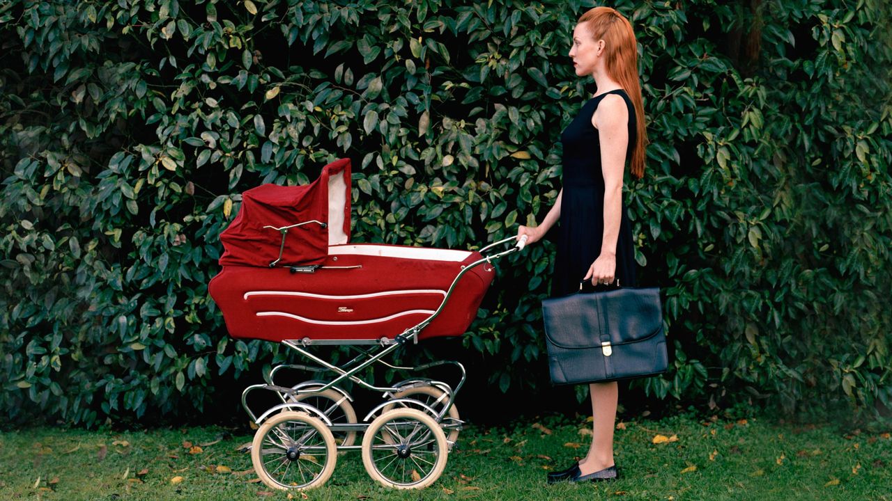 Woman in business attire pushing a pram.