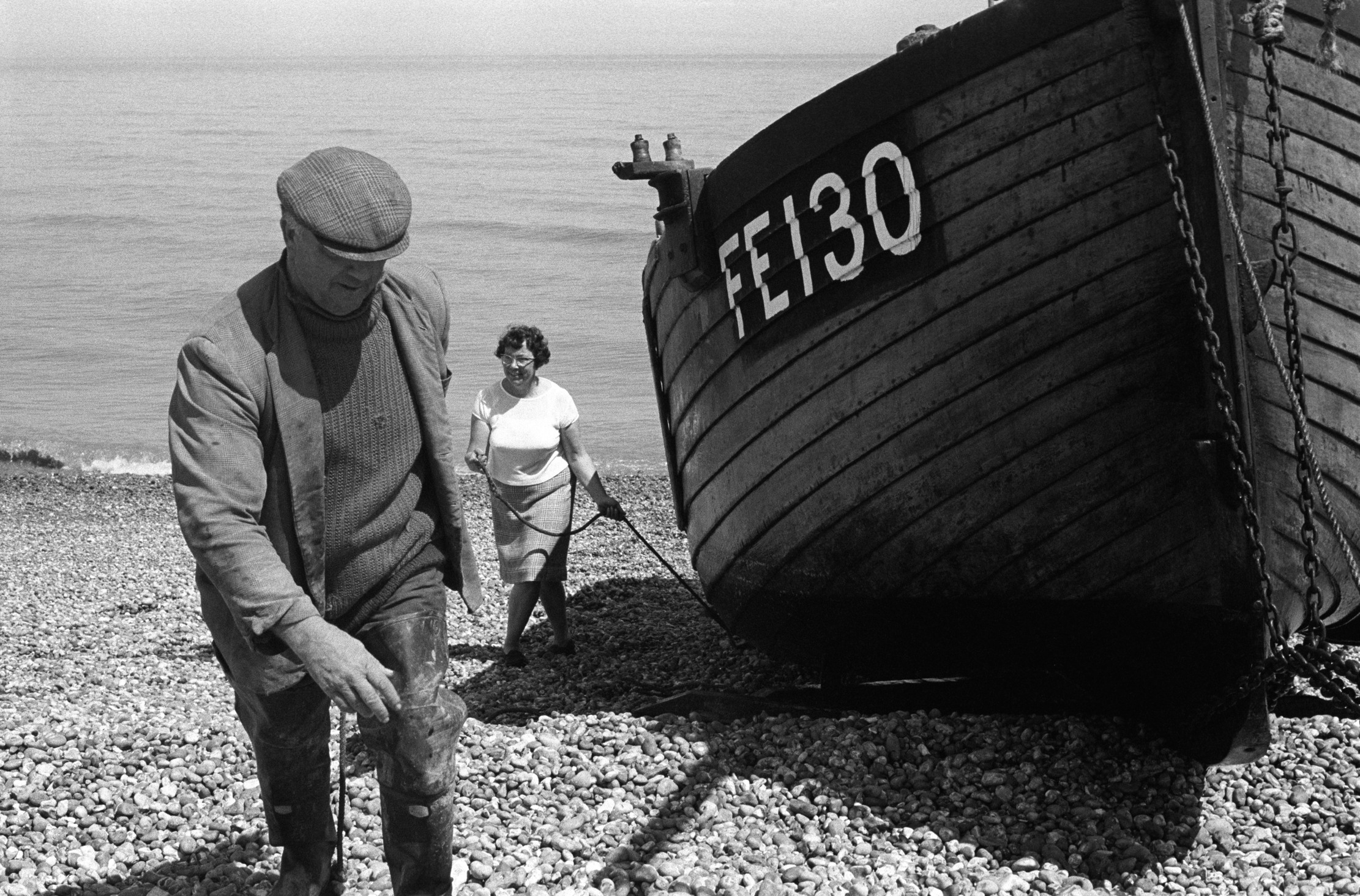 A fisherman drags a boat up the shore
