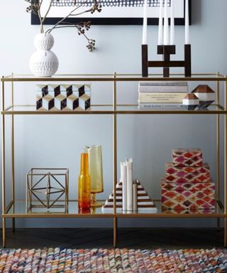 A gold console table with colorful decor on it