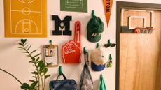 Dorm room decor, including a foam finger, collegeate monogram letter, ball caps, and posters, mounted to a wall alongside a mini basketball hoop, which is mounted to the door