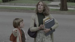 Laurie Strode walks down the street in Halloween's iconic opening scene.