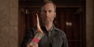 Bob Odenkirk holds some burning money in Nobody.