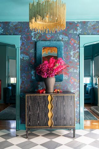 A bold blue patterned wallpaper in the entryway, with blue paint around the doorways and a large blue mirror