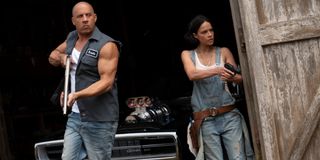 Vin Diesel and Michelle Rodriguez storming out of the barn guns drawn in F9.