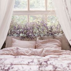 lavender plants at bedroom window behind bed with white pillows and blankets