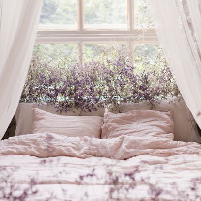 lavender plants at bedroom window behind bed with white pillows and blankets