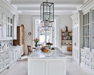 Galley kitchens illustrated by a large neutral room with marble island and wooden furniture.