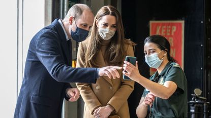Prince William, Duke of Cambridge and Catherine, Duchess of Cambridge talk with the family of paramedic Jahrin (Jay) Khan via a mobile phone during a visit to Newham ambulance station in East London on March 18, 2021 in London, England