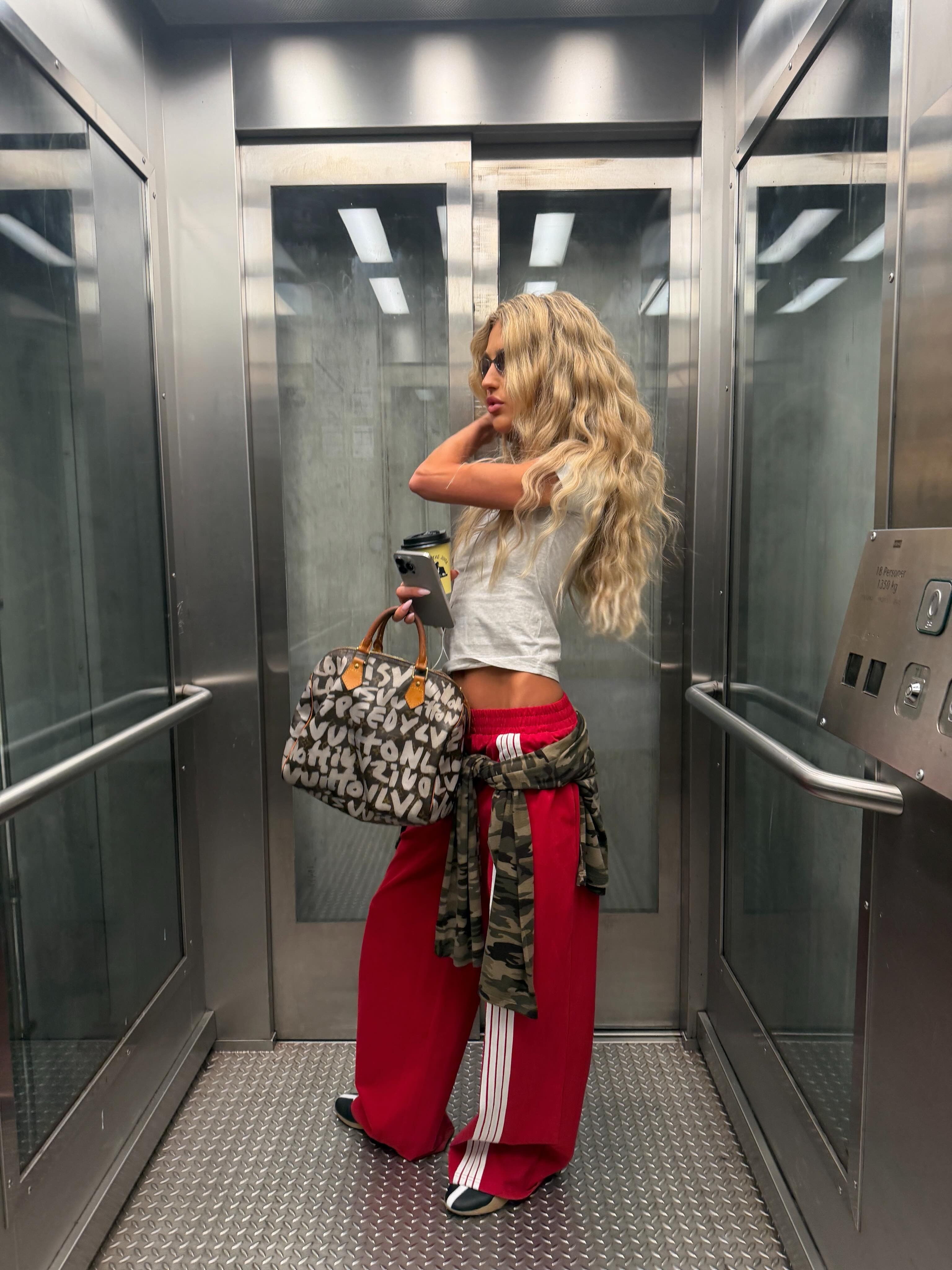 @emilisindlev wearing Lioness track pants, Adidas sneakers, and a T-shirt
