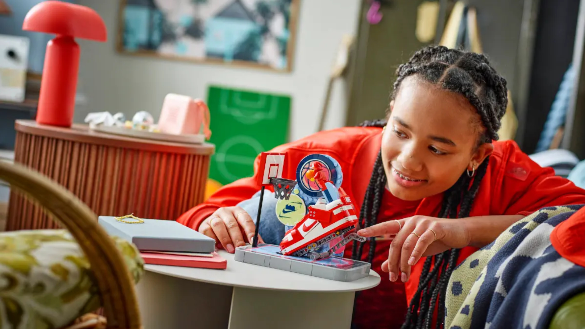 A girl smiles while pressing the Nike Dunk Trickshot Lego set at a table