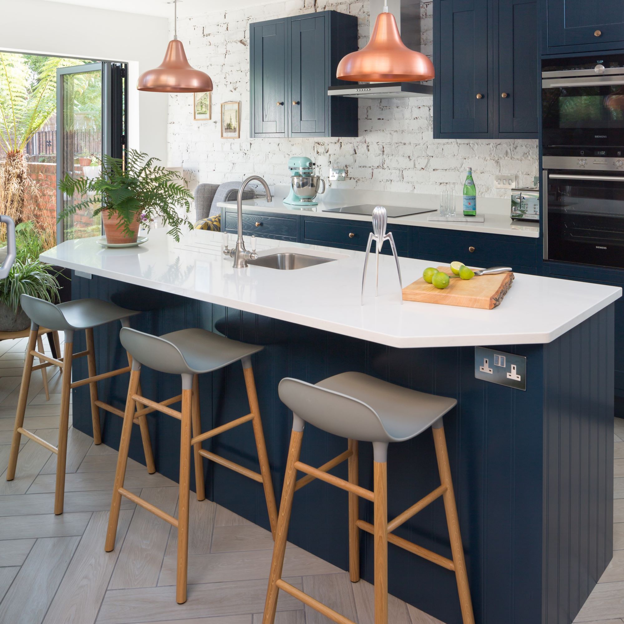 Navy blue kitchen island with white countertop underneath lights