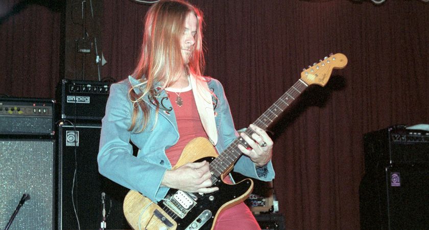 A young Steve Morse wears a red T-shirt and matching pants, and a light-blue jacket as he plays his FrankTele live in 1983.