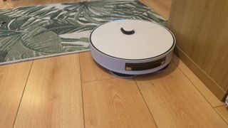 Samsung Bespoke Jet Bot Combo AI håller på att dammsuga längs en möbelkant.