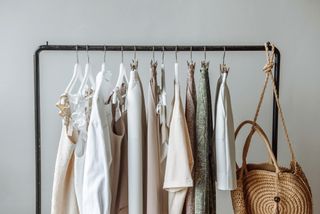 A metal clothes rail with a variety of neutral, pastel clothing on.