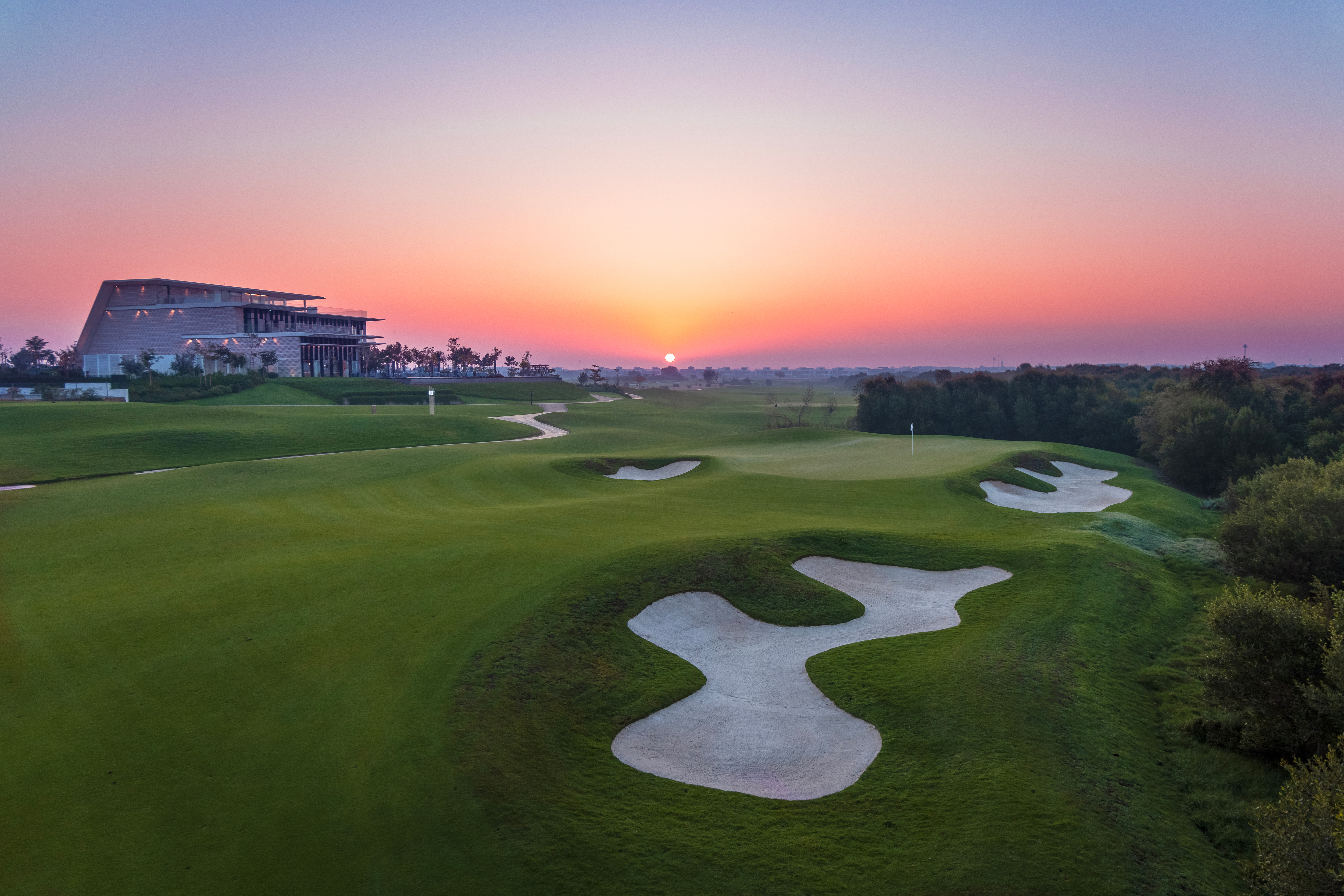 A general view over the 18th green and of Al Zorah's clubhouse at sunset